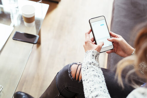 Niedriger Ausschnitt einer Geschäftsfrau, die im Büro ein Mobiltelefon benutzt - CAVF25555