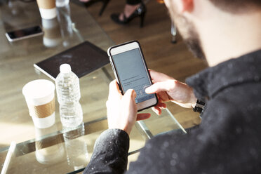 Blickwinkel eines Geschäftsmannes, der ein Mobiltelefon im Büro benutzt - CAVF25559