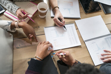 Cropped image of colleagues discussing graphs at table in office - CAVF25588