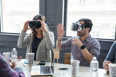 Kollegen tragen einen Virtual-Reality-Simulator, während sie im Büro sitzen - CAVF25593