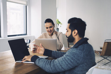 Business people using laptop computers while sitting at desk in office - CAVF25614