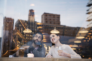 Ein Paar genießt ein Getränk, während es durch ein Restaurantfenster wegschaut - CAVF25643