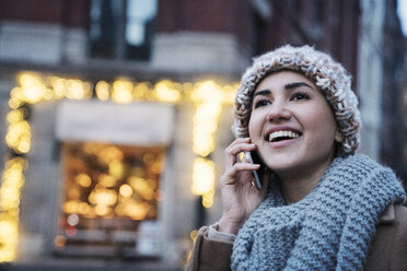 Close-up of happy woman talking on mobile phone in city - CAVF25651