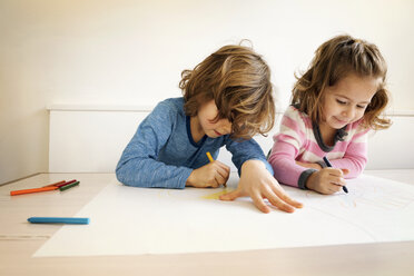 Siblings drawing at table in home - CAVF25656