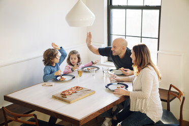 Familie genießt beim Pizzaessen am Esstisch im Haus - CAVF25660