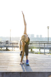 Woman exercising on floorboard against clear sky - CAVF25899