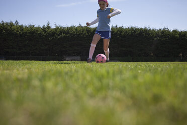 Mädchen übt Fußball auf einer Wiese - CAVF25929