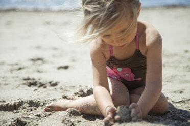 Mädchen spielt mit Sand am Strand an einem sonnigen Tag - CAVF25935