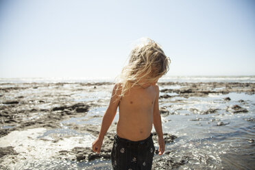 Girl standing on wet sand at beach against clear sky - CAVF25936