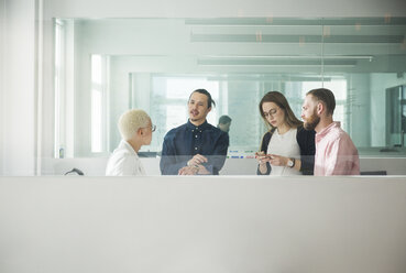 Kollegen diskutieren im Büro durch ein Fenster gesehen - CAVF26040