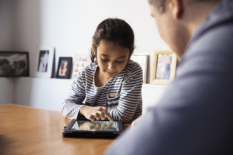 Ausgeschnittenes Bild eines Vaters, der seine Tochter mit einem Tablet-Computer betrachtet, lizenzfreies Stockfoto