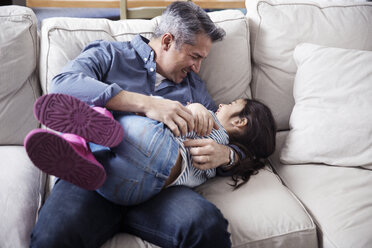 Fröhlicher Vater und Tochter genießen auf dem Sofa zu Hause - CAVF26065