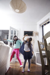 Verspielte Mädchen mit Augenmasken und Umhängen, während sie zu Hause stehen - CAVF26069