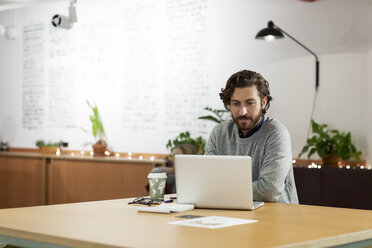 Businessman using laptop computer at table in office - CAVF26099