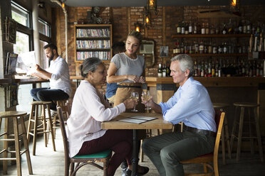 Kellnerin im Gespräch mit Kunden, die im Café sitzen - CAVF26162