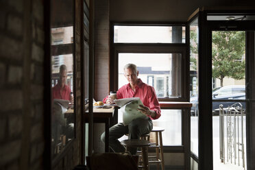 Älterer Mann liest Zeitung und trinkt Kaffee in einem Cafe - CAVF26173