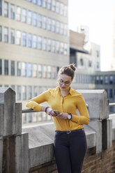 Businesswoman using mobile phone while standing in balcony - CAVF26219