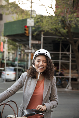 Porträt einer glücklichen Geschäftsfrau mit Fahrrad auf der Straße, lizenzfreies Stockfoto