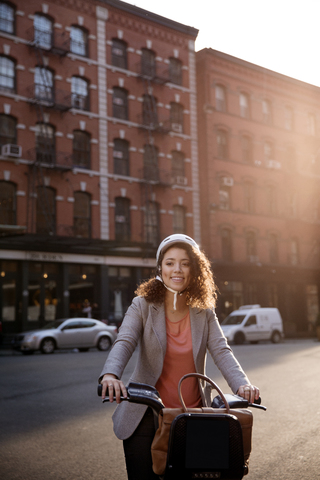 Glückliche Geschäftsfrau hält Fahrrad auf der Straße, lizenzfreies Stockfoto