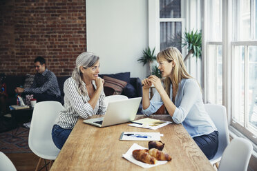 Businesswomen discussing at conference table in creative office - CAVF26285