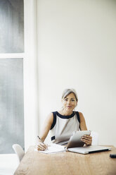 Porträt einer selbstbewussten Geschäftsfrau, die am Konferenztisch arbeitet - CAVF26302
