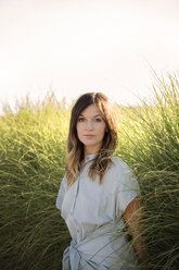 Portrait of confident woman standing by grass against clear sky - CAVF26309