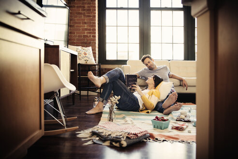Lächelndes Paar entspannt sich zu Hause auf dem Teppich - CAVF26313