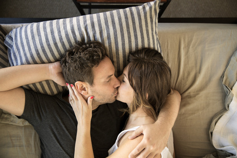 Hohe Winkel Ansicht des Paares küssen, während auf dem Bett liegend, lizenzfreies Stockfoto