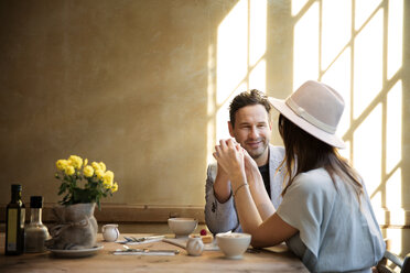Glückliches Paar hält sich an den Händen und sitzt am Tisch im Restaurant - CAVF26331