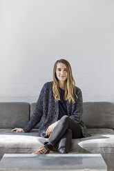 Porträt einer selbstbewussten Geschäftsfrau, die auf einem Sofa an der Wand im Büro sitzt - CAVF26357