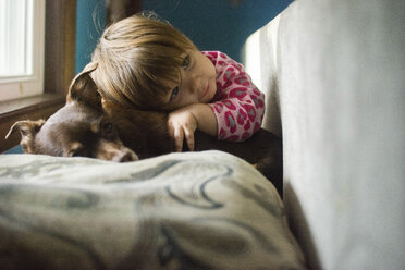 Girl lying on dog at home - CAVF26371