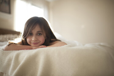 Portrait of smiling girl lying on bed at home - CAVF26402