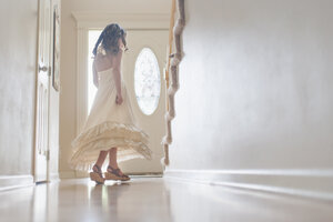 Mädchen im Kleid, das sich zu Hause vor der Tür dreht - CAVF26421