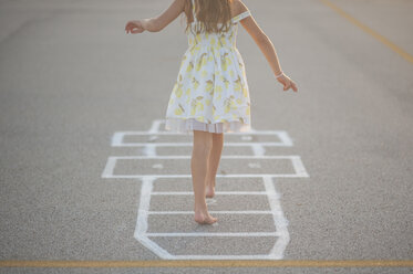 Low section of girl playing hopscotch on footpath - CAVF26428