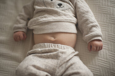 Midsection of baby boy lying on bed at home - CAVF26451