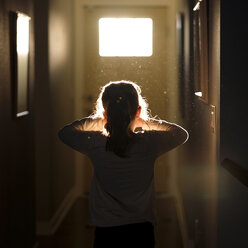 Rear view of girl standing in corridor at home - CAVF26465