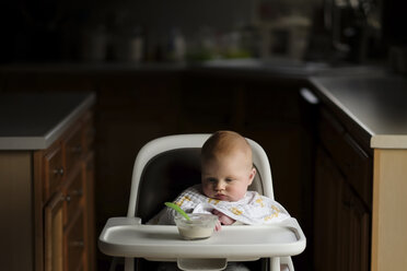 Baby boy looking at food in bowl while sitting on high chair - CAVF26466