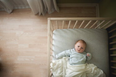 Draufsicht auf einen kleinen Jungen in einem Kinderbett zu Hause - CAVF26468