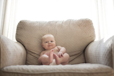 Porträt eines kleinen Jungen, der zu Hause auf einem Sessel am Fenster sitzt - CAVF26472