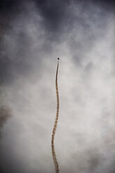 Entfernte Ansicht eines Militärflugzeugs, das in einem bewölkten Himmel fliegt - CAVF26523