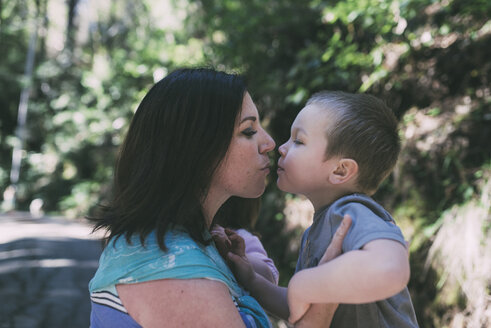 Seitenansicht von Mutter und Sohn, die sich im Park küssen - CAVF26681