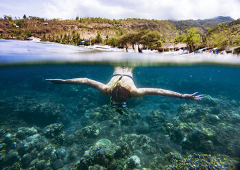 Woman snorkeling in sea against mountain - CAVF26690