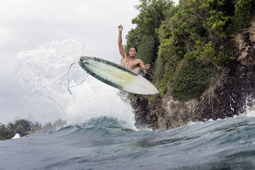 Junger männlicher Surfer springt über das Meer - CAVF26695