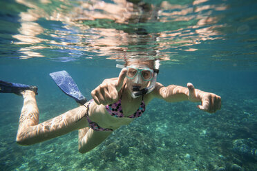 Portrait of successful woman showing thumbs up while snorkeling in sea - CAVF26709
