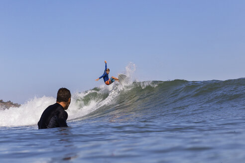 Mann schaut auf Freund Surfen auf dem Meer gegen klaren blauen Himmel - CAVF26727