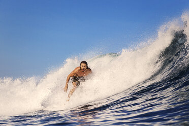 Mid adult man surfing in sea against clear blue sky - CAVF26735