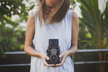 Woman holding vintage camera at yard - CAVF26741