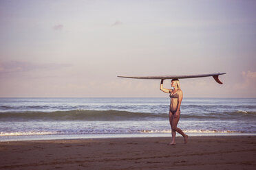 Frau mit Surfbrett am Ufer gegen den Himmel - CAVF26745