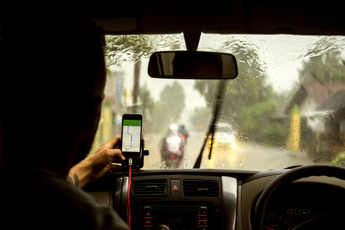 Mann, der im Auto sitzend eine Navigationskarte auf seinem Mobiltelefon benutzt - CAVF26758
