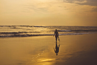 Silhouette einer Frau mit Surfbrett, die am Strand spazieren geht - CAVF26765
